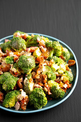 Homemade Broccoli Bacon Salad on a Plate on a black background, side view.