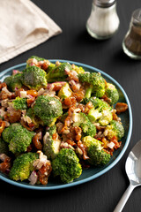Homemade Broccoli Bacon Salad on a Plate on a black background, side view.