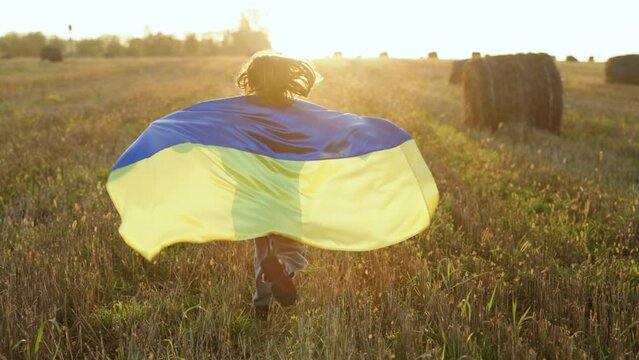 Cute little girl Ukrainian patriotic child runs with national flag of Ukraine showing political position. Stop war in Ukraine. Support, stand with Ukraine, Save, Help, Pray for Ukraine