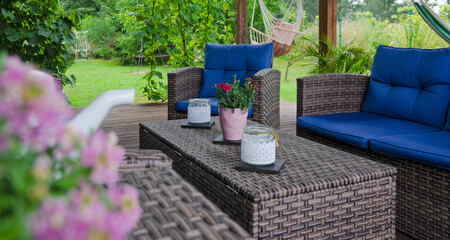 Natural cozy covered terrace with green nature in summer. Rattan and wicker furniture with...