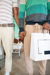 Close-up of two mens hands holding together. Two African American men holding hands together, enjoying leisure making purchases. LGBT couples relations, equality and shopping concept