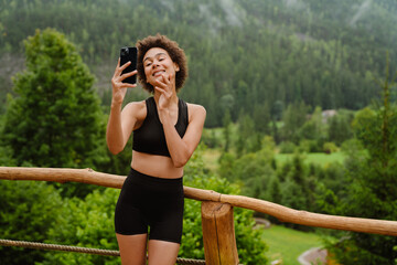Curly woman taking photo on cellphone after yoga practice