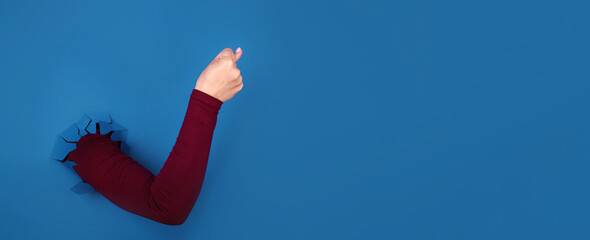 Hand showing the fig sign over blue background, panoramic layout