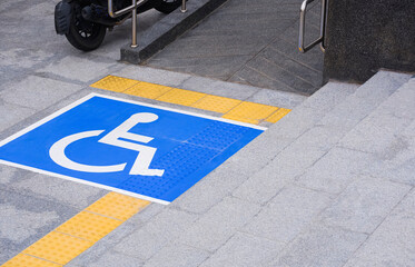Disabled wheelchair sign with ramp and yellow tactile paving line on different level marble...
