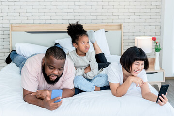 A 5-year-old African-American girl, showing up in a bad mood because her parents are not interested, and using mobile phones all the time, to family and social media concept.