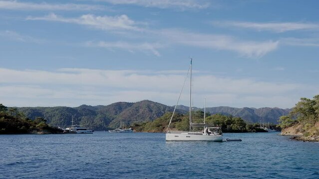 Beautiful bay with sailing boat, yacht in turquoise sea and mountains, luxury holidays or sailing regata sports.