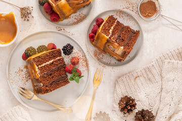 Delicious semi-naked chocolate cake with caramel topping and decorated with blackberries and raspberries. Light background