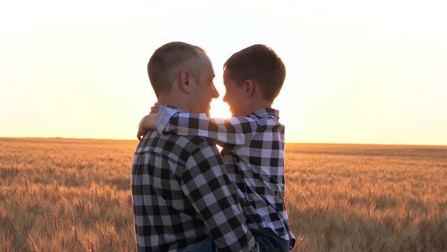 Dad holds the baby in his arms. Father and son look at each other and laugh. Happy family at sunset. Kid dreams.