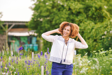 Outdoor portrait of beautiful 50 year old woman enjoying nice day in flower park or garden, happy...