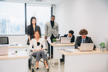 Businesswoman holding a meeting, conference, and conversation with his team while seated in a wheelchair at the workplace.