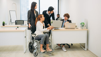 Businesswoman holding a meeting, conference, and conversation with his team while seated in a wheelchair at the workplace.