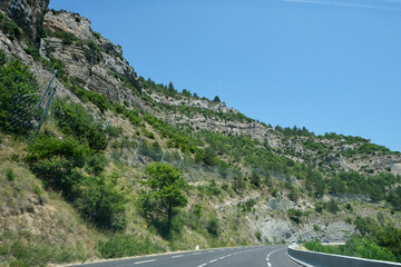 Mountain with safety fence to protect the road and cars from falling rocks. Heavy duty wire netting used to catch falling rocks from the cliffs in order to protect the cars driving on the highway.
