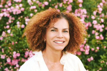 Outdoor close up portrait of beautiful middle age woman posing in garden at sunset