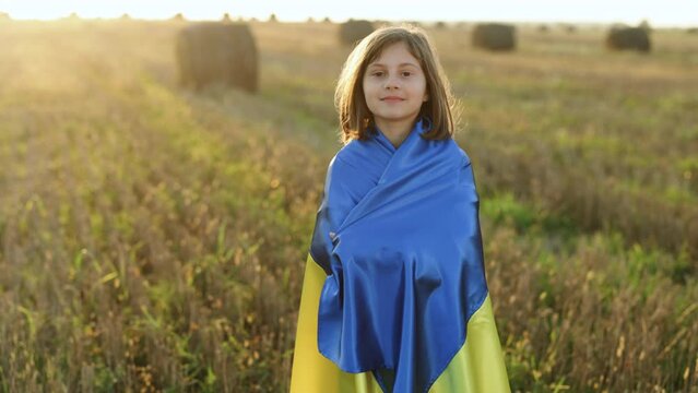 Outdoor portrait of young girl with blue and yellow ukrainian flag. Stop war in Ukraine. Russia stop war. Kid standing outdoors at sunset. International day of democracy concept. Flag Day