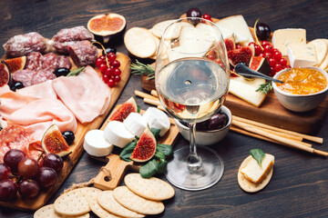 Food antipasto prosciutto ham, salami, olives and grissini bread sticks. cheese on a board parmesan, pecorino, gorgonzola. Charcuterie board.  glass of white wine or prosecco
