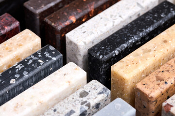 Porcelain stoneware square samples laid on kitchen countertop as examples of future kitchen fasade exterior. Samples slabs of natural granite marble quartz for stone countertops close up diagonal.