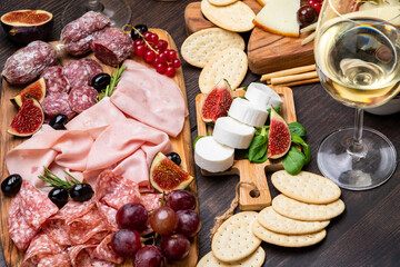 Food antipasto prosciutto ham, salami, olives and grissini bread sticks. cheese on a board parmesan, pecorino, gorgonzola. Charcuterie board.  glass of white wine or prosecco