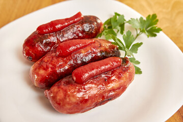 Fried sausages with ketchup on a white plate.