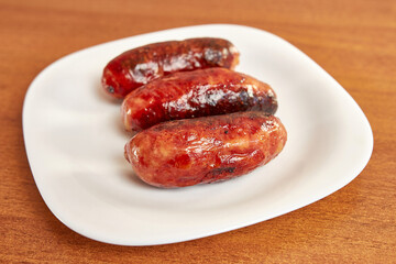 Fried sausages on a white plate.