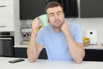 Sleepy looking man holding coffee cup in the kitchen 