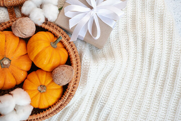 Autumn mood wallpaper with space for text on bright white background. Orange baby pumpkin in bohemian basket. Crafty decorated gift box, modern eco gift. Thanksgiving day greeting card. Invitation