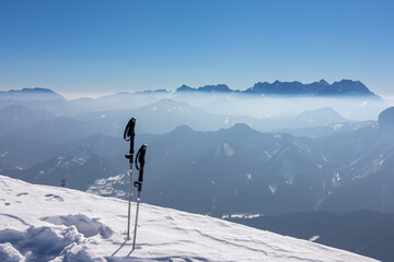 Hiking stick in snow. Scenic view from summit Freiberg on misty snow capped mountain peaks in Karawanks mountains, Carinthia, Austria. Winter wonderland on sunny day in Austrian Alps, Europe. Ski tour