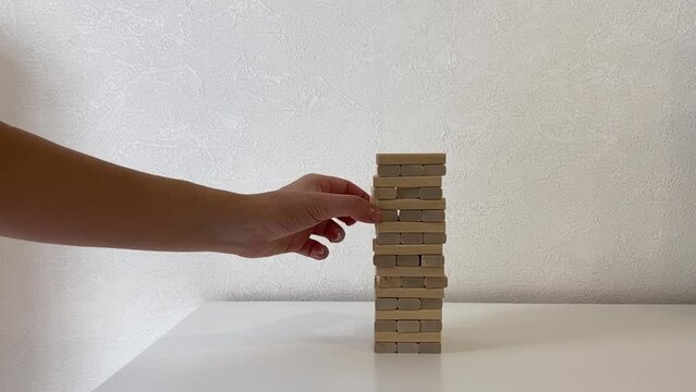 Jenga game. In the video, a woman's hand pushes away wooden jenga dice.