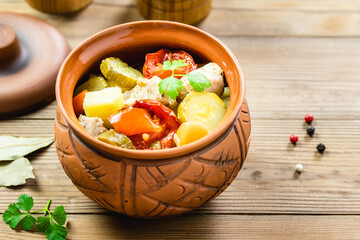 Stewed turkey and vegetables in a pot on wooden background. Top view, flat lay, copy space.