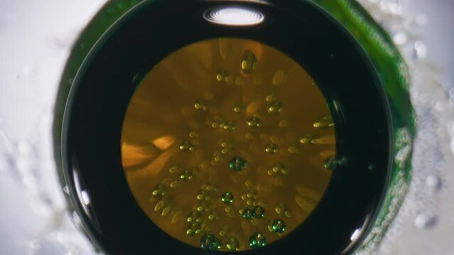 Iced ipa splattering bottle closeup. Golden ale splashing flask slow motion