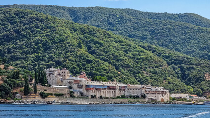 Fototapeta na wymiar Scenic view from boat on Xenophontos monastery at Mount Athos in Autonomous Monastic State of Holy Mountain, Chalkidiki, Central Macedonia, Greece, Europe. Holy Eastern Orthodox terrain of Again Oros