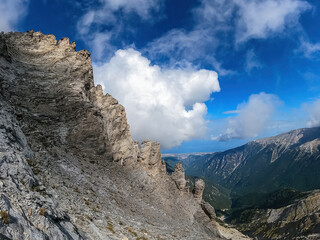 Fototapeta premium Climbing on mystical foggy hiking trail leading to Mount Olympus (Mytikas, Skala, Stefani, Skolio), Mt Olympus National Park, Macedonia, Greece, Europe. Scenic view of cloud covered cliffs and ridges