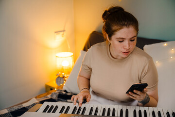 Young beautiful focused girl playing electronic piano