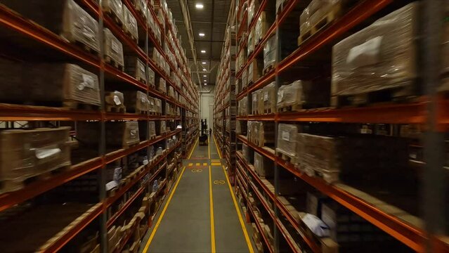 High racks with cardboard boxes and forklift loader in spacious warehouse first point view. Plant products storage