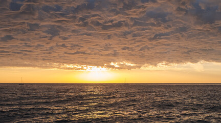 Amazing clouds in the sky on the sea and the rays of the setting sun