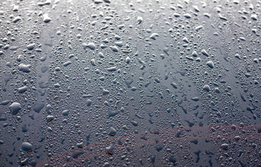 Dew drops on the black hood of a parked car. Background
