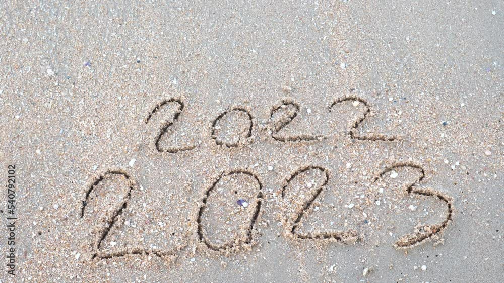 Wall mural message year 2022 replaced by 2023 written on beach sand background. goodbye 2022 hello to 2023 lapp