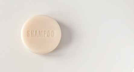 closeup of isolated round shape dry handmade shampoo bar with note 'shampoo' on white gray background, made of cold pressed oil, vegan formula. No plastic, natural ingredients. Copy space on right.