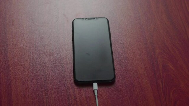 cell phone charging on a wooden table
