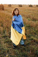 Portrait of Ukrainian little girl with Ukrainian flag. Support for Ukraine. Girl in patriotic clothes. War in Ukraine. Stop the war. A Ukrainian woman holds the slug of her country in her hands