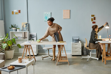 African young businesswoman preparing for lunch at her workplace at office, she putting lunch box...