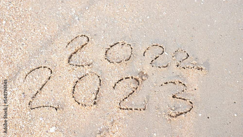 Wall mural message year 2022 replaced by 2023 written on beach sand background. goodbye 2022 hello to 2023 lapp