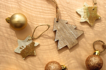 Christmas tree ornaments in neutral and gold colors, illuminated by sunlight. Flat lay.