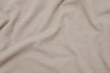 Creased and wrinkled fabric texture closeup. Beige shirt material. Flat lay, top view. 