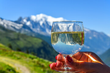 A glass of white wine in hand against the backdrop of Mont Blanc. France, Chamonix.