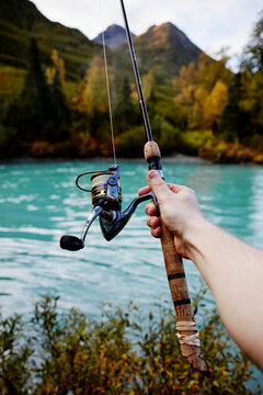 autumn river salmon fishining with a rod and reel with a corck handle and fishing line in blue alaskan river in alaska