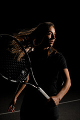 Great portrait of woman with brown flowing hair in black tennis uniform with tennis racket
