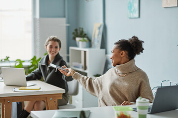 Obraz premium Colleagues cooperating together at office while sitting at their desks with computers