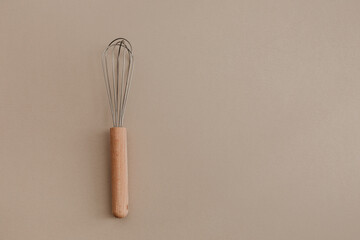 A wooden whisk beater on beige paper background. Flat lay, top view copy space. Natural light,...