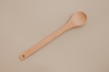 A wooden spoon on beige paper background. Copy space, flat lay photo. 