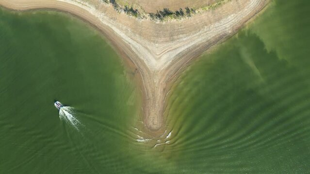 Aerial top view of the peninsula that washes the ocean, the waves wash the sandy shore, boat sailing on the sea.